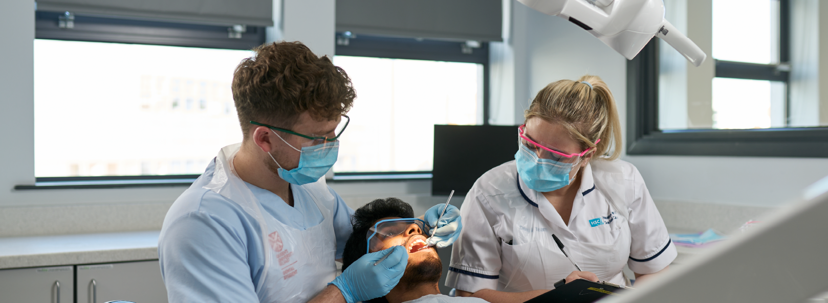 A student performs dental treatment under staff supervision.